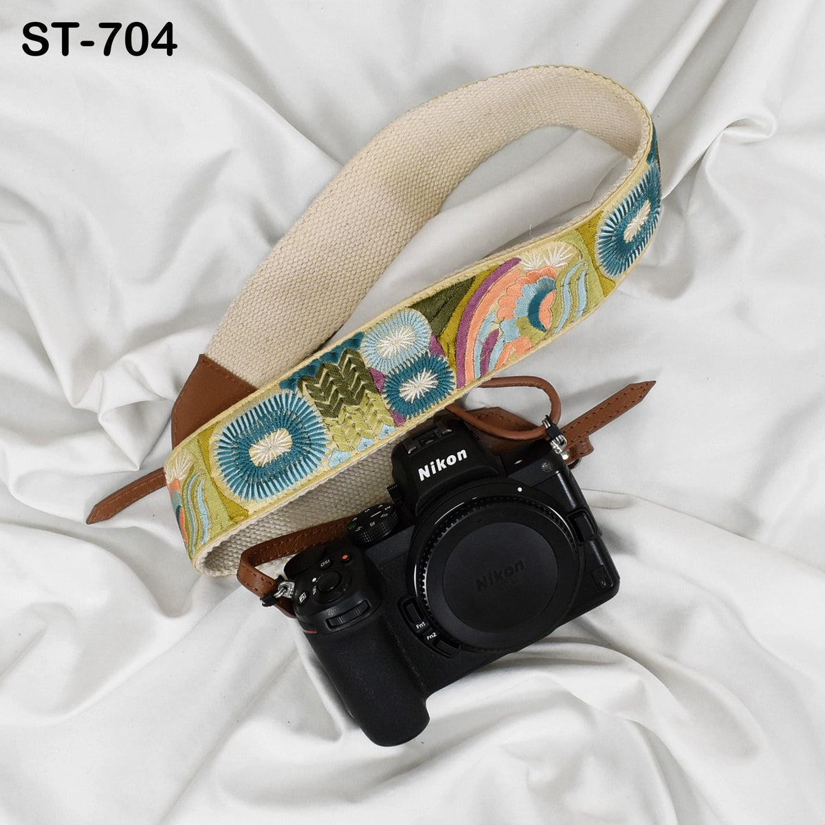 A black camera with a colorful strap is placed on a white surface.