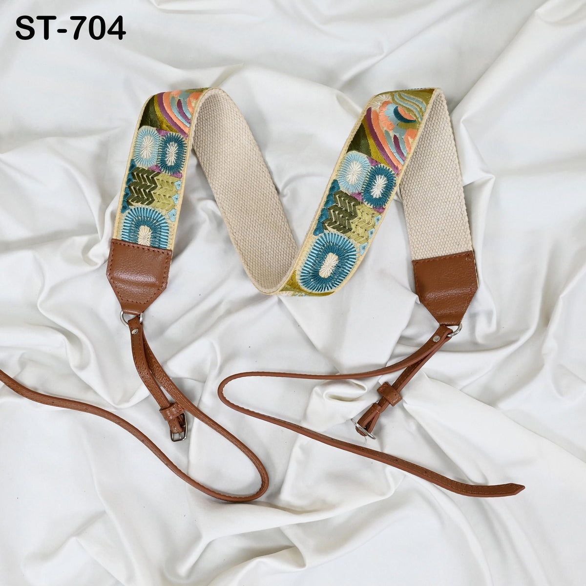 a colorful, patterned strap with a brown leather buckle, placed on a white fabric surface.