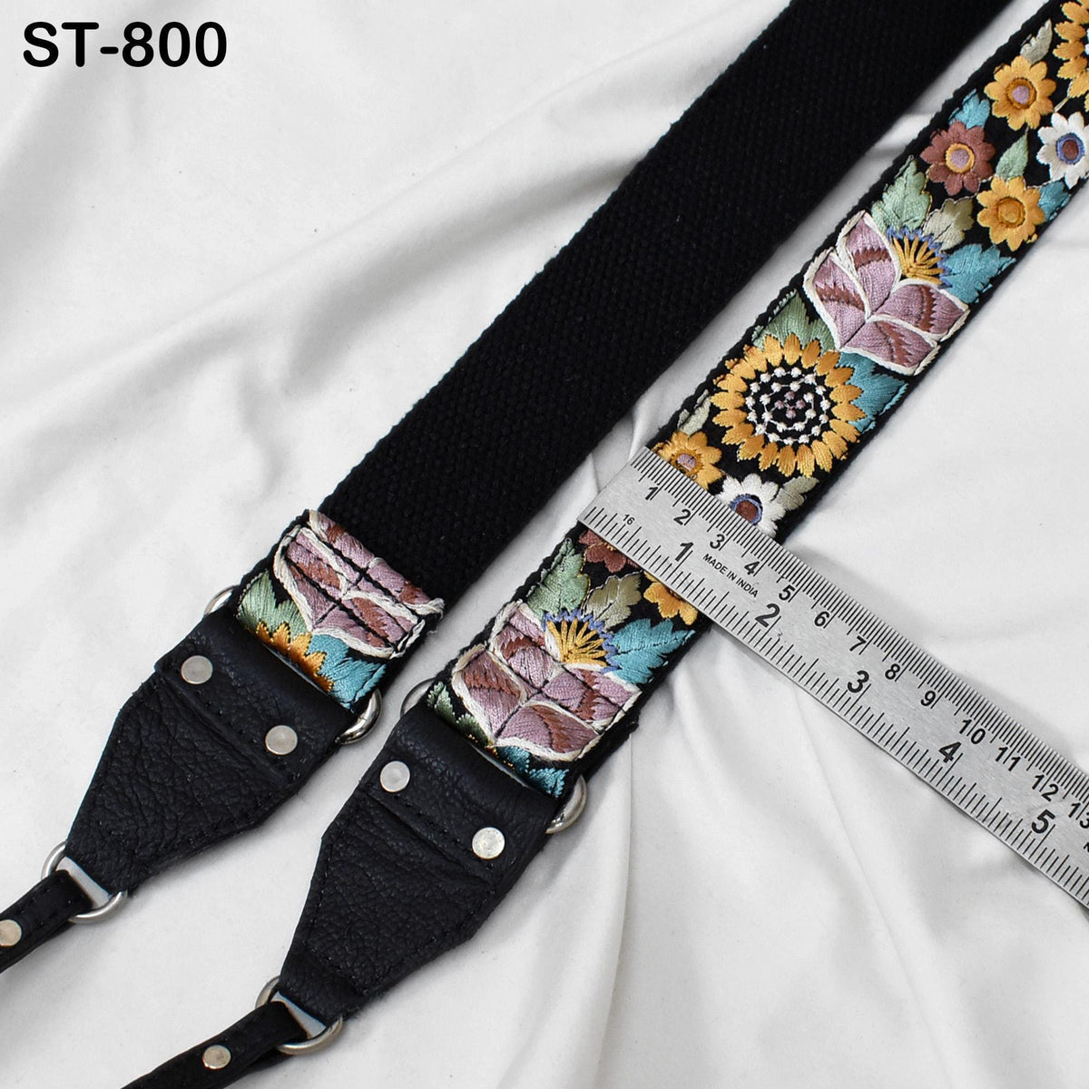 A black strap with a floral pattern and a ruler placed on top of it.