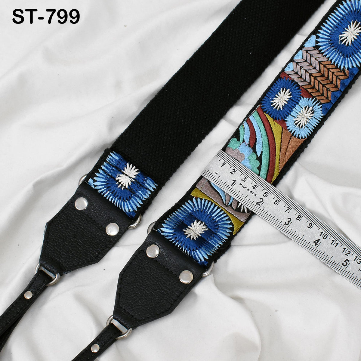 A black strap with a colorful floral embroidered pattern, and a ruler placed next to it, indicating the strap's length.