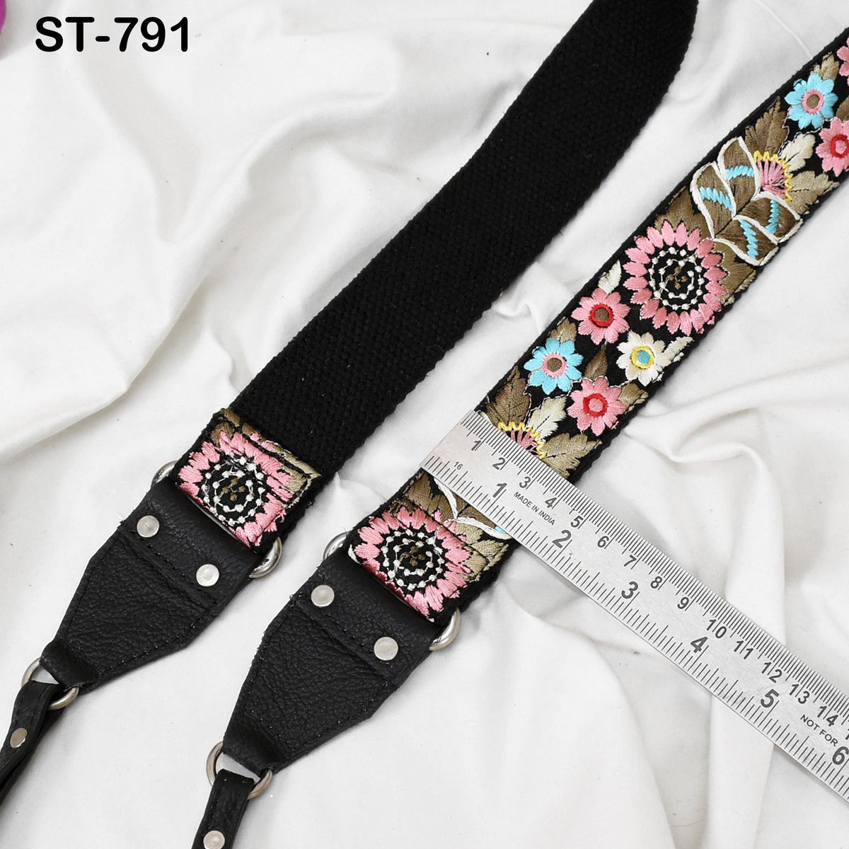 A black strap with a floral pattern and a ruler placed next to it on a white background.
