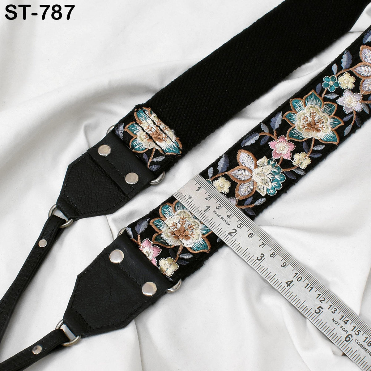 A black strap with a floral pattern and a ruler placed next to it on a white background.