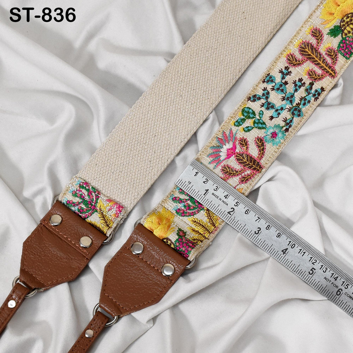 a beige strap with a floral pattern, placed on a white fabric surface. A ruler is visible next to the strap, indicating its size.