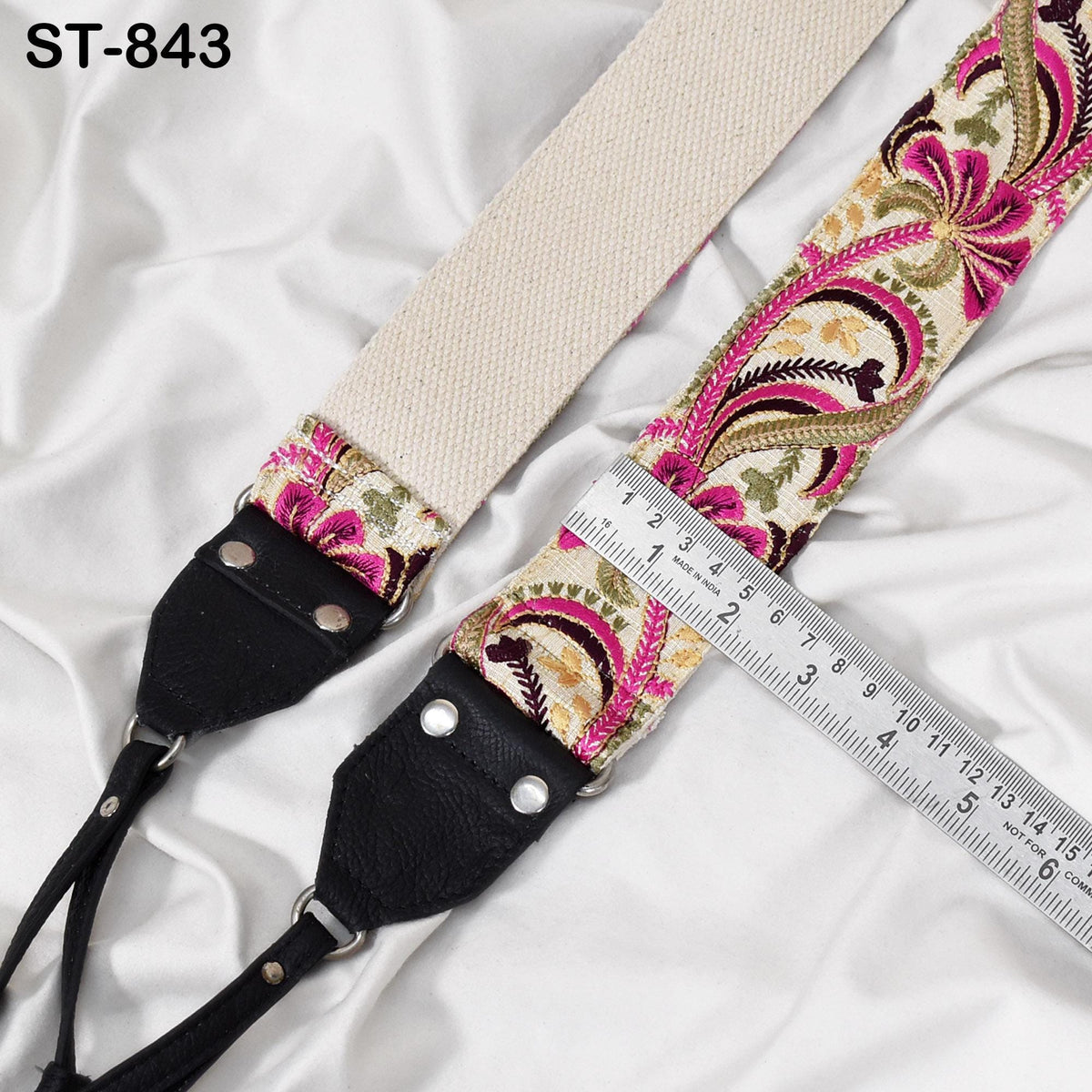 A camera strap with a floral pattern and a ruler placed on top of it.