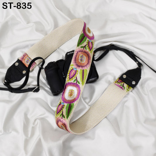 A camera strap with a floral pattern is placed on a white surface.