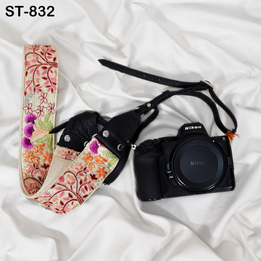 A floral patterned camera strap and a Nikon camera are placed on a white surface.