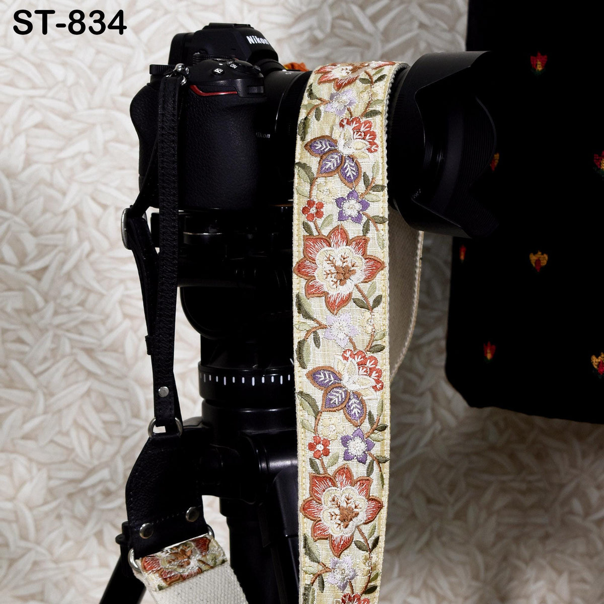 A black camera with a floral patterned strap is shown in the image.