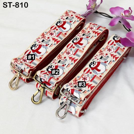 Three colorful straps with snowman and Christmas-themed patterns are displayed on a white surface, accompanied by purple flowers.