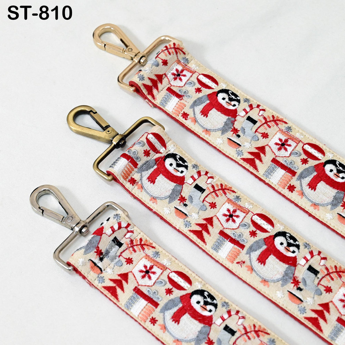 three straps with a festive pattern of penguins and snowflakes. The straps have metal hooks and buckles, and the straps are arranged in a row.