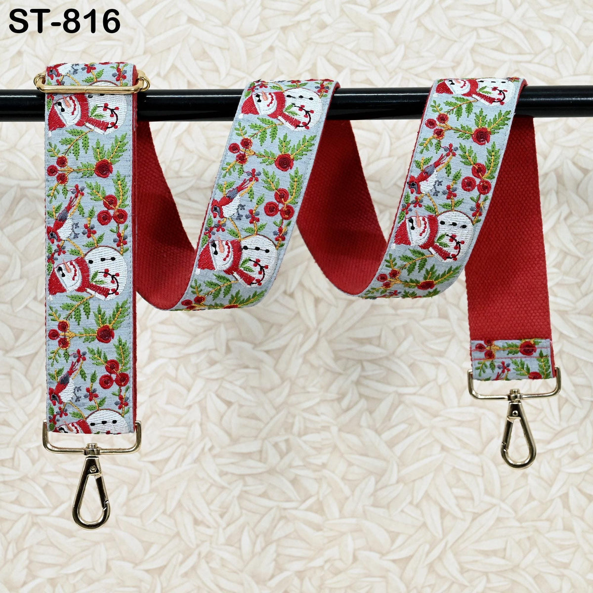 A red and white patterned strap with snowmen and flowers, hanging on a black pole.