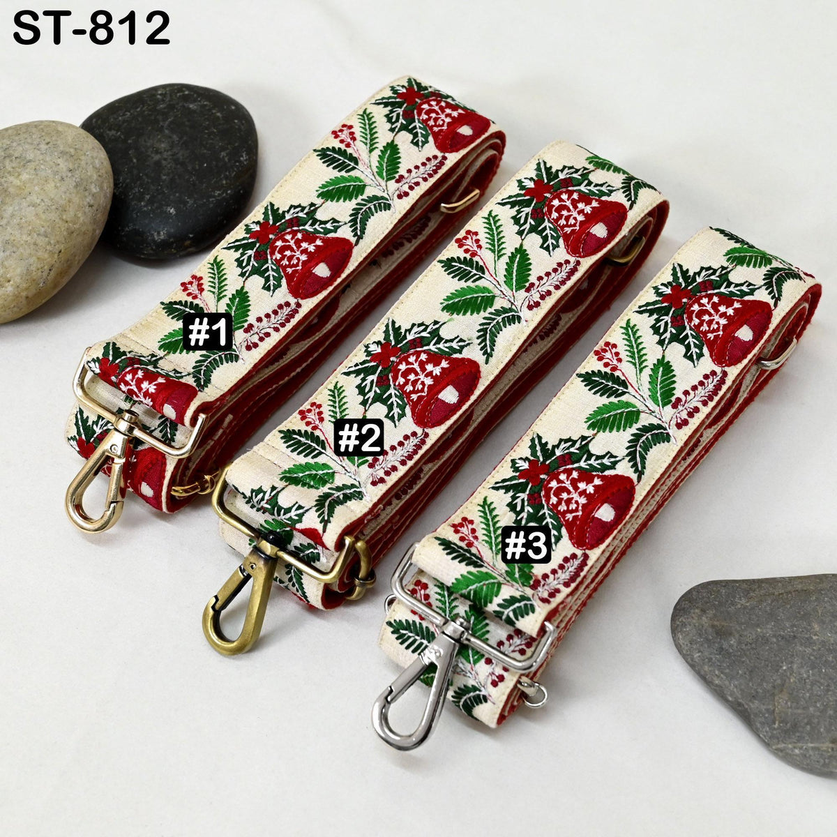 three straps with a floral pattern, each with a different number printed on it. The straps are placed on a surface with some rocks and a stone.