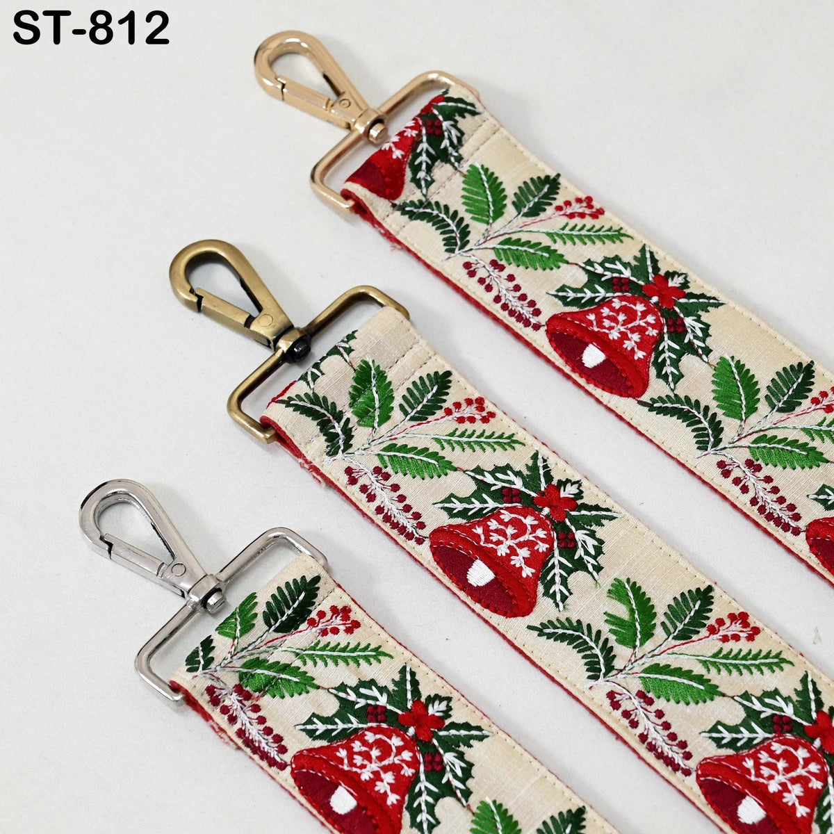 three straps with a festive holiday pattern, featuring red and green leaves, red berries, and a bell motif. The straps appear to be made of fabric and have metal hooks or buckles attached to them.