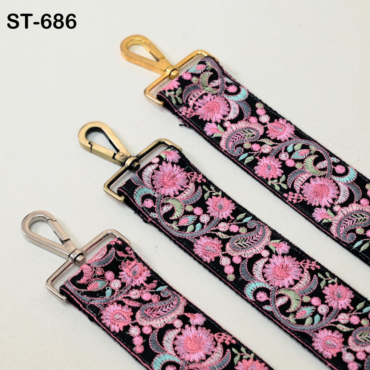 three colorful straps with floral patterns, each featuring a gold metal hook and a silver metal loop.