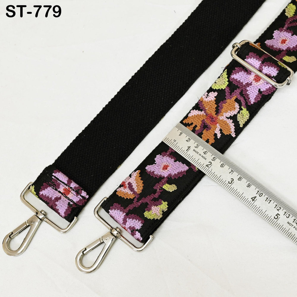 a black strap with a floral pattern and a metal ruler placed on top of it.