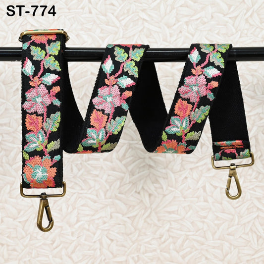 A floral-patterned black strap with a gold-colored buckle, hanging on a black pole.