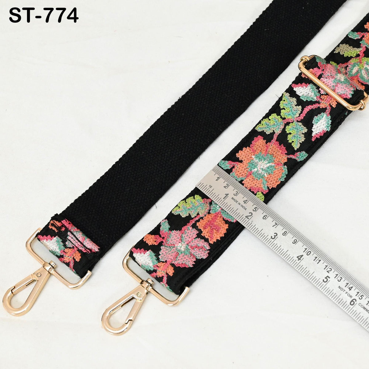 a floral-patterned black strap with a metal clasp and a ruler placed next to it, indicating the strap's size.
