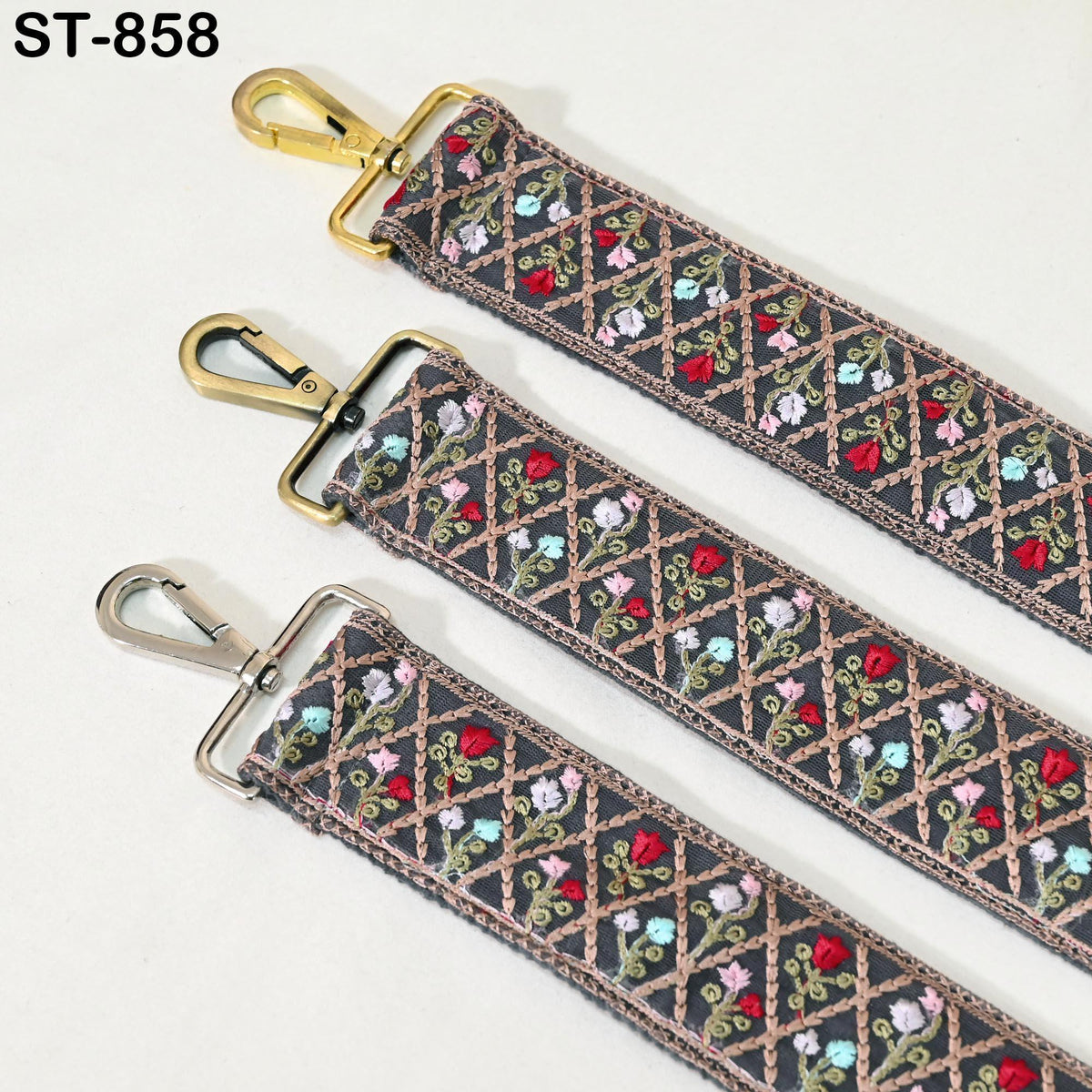 three straps with a floral pattern, each with a metal clasp and hook. The straps appear to be made of a dark fabric with a decorative floral design.