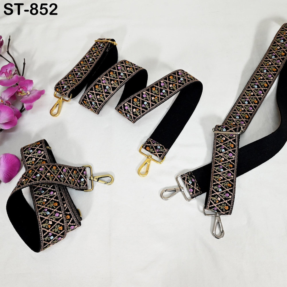 a collection of black and gold patterned straps, including a black strap with a gold clasp and a black strap with a gold clasp, arranged on a white surface.