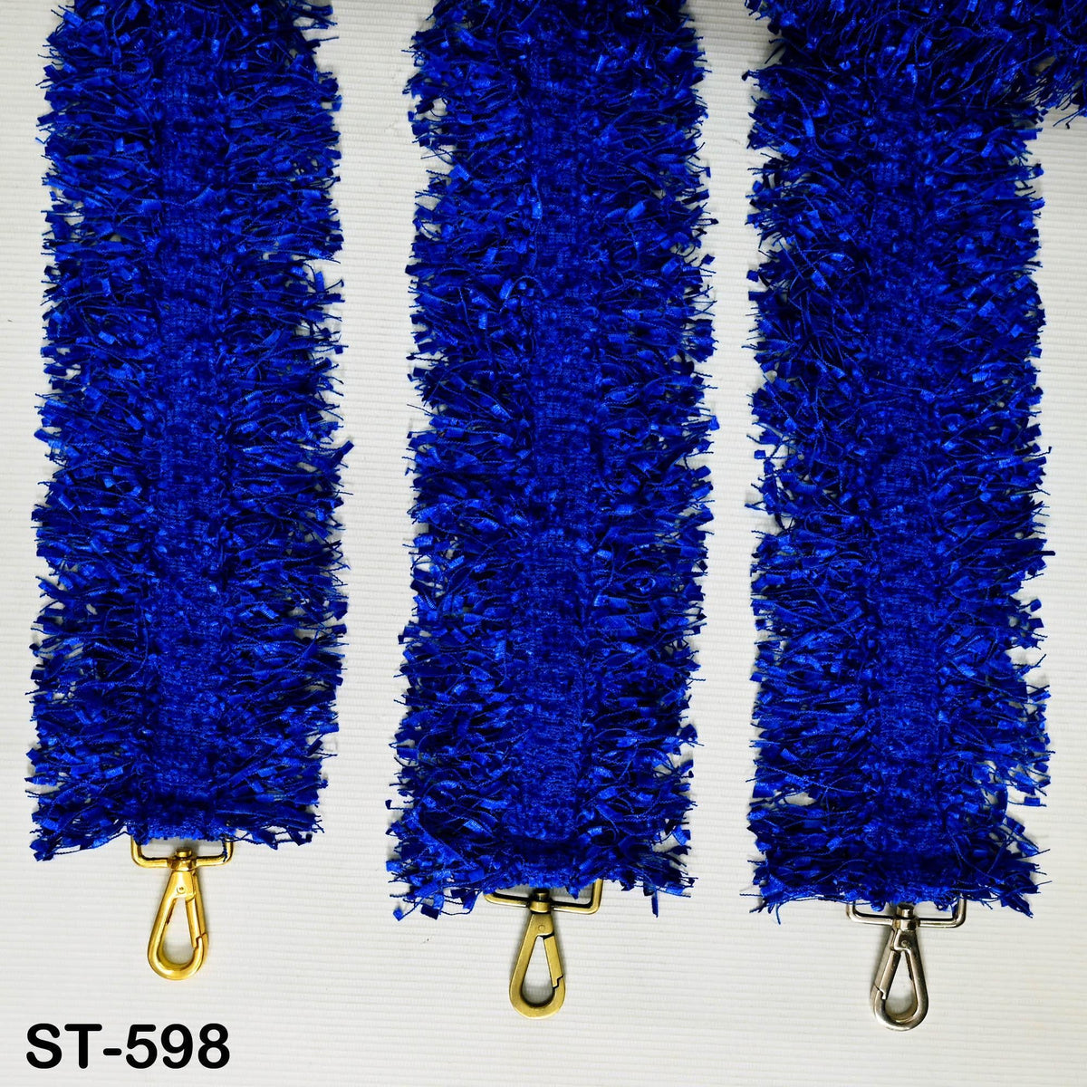 Three blue, fluffy, metallic objects are arranged in a row, with a gold-colored clasp visible at the bottom.