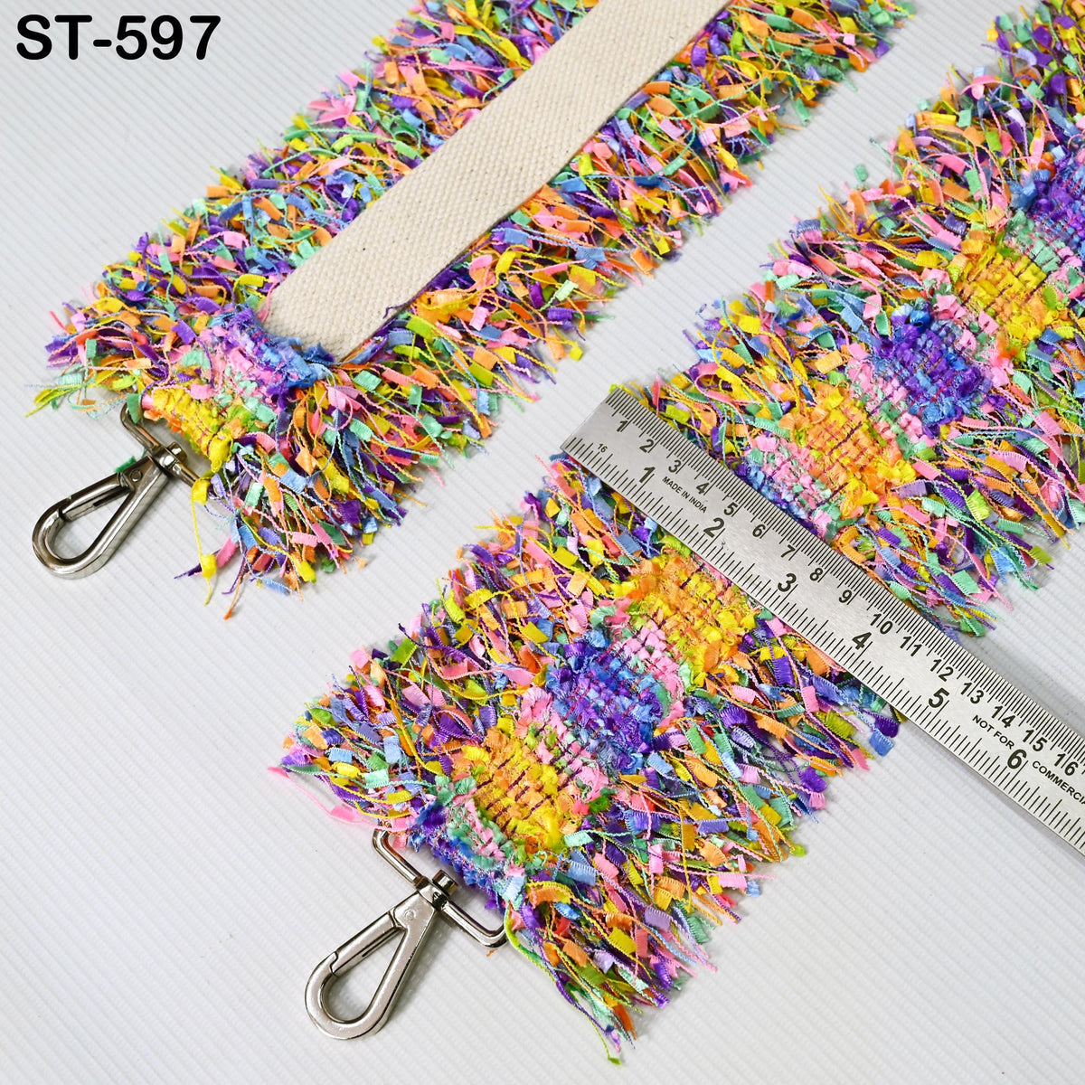a colorful, textured strap with a metal clasp and a ruler placed on top of it.