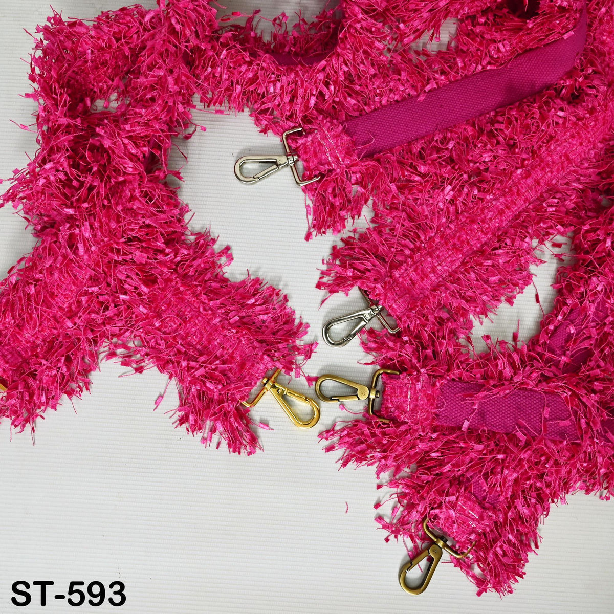 a pink, fuzzy accessory with multiple hooks and buckles, including a pink strap and a pink clasp.