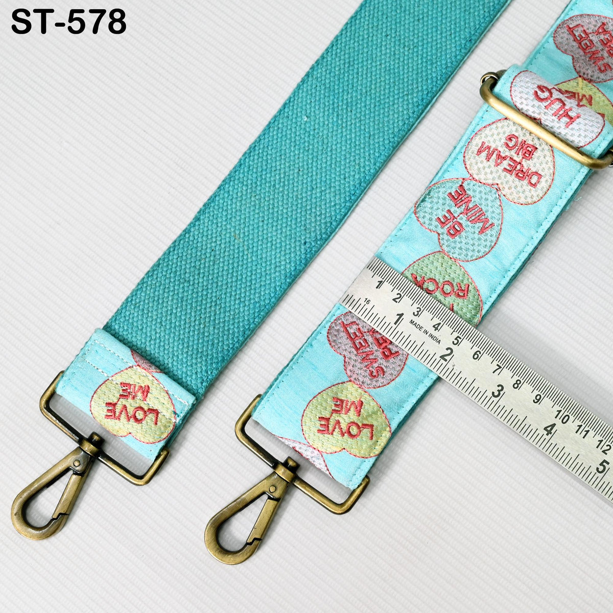 a turquoise strap with a metal clasp and a ruler placed on top of it.