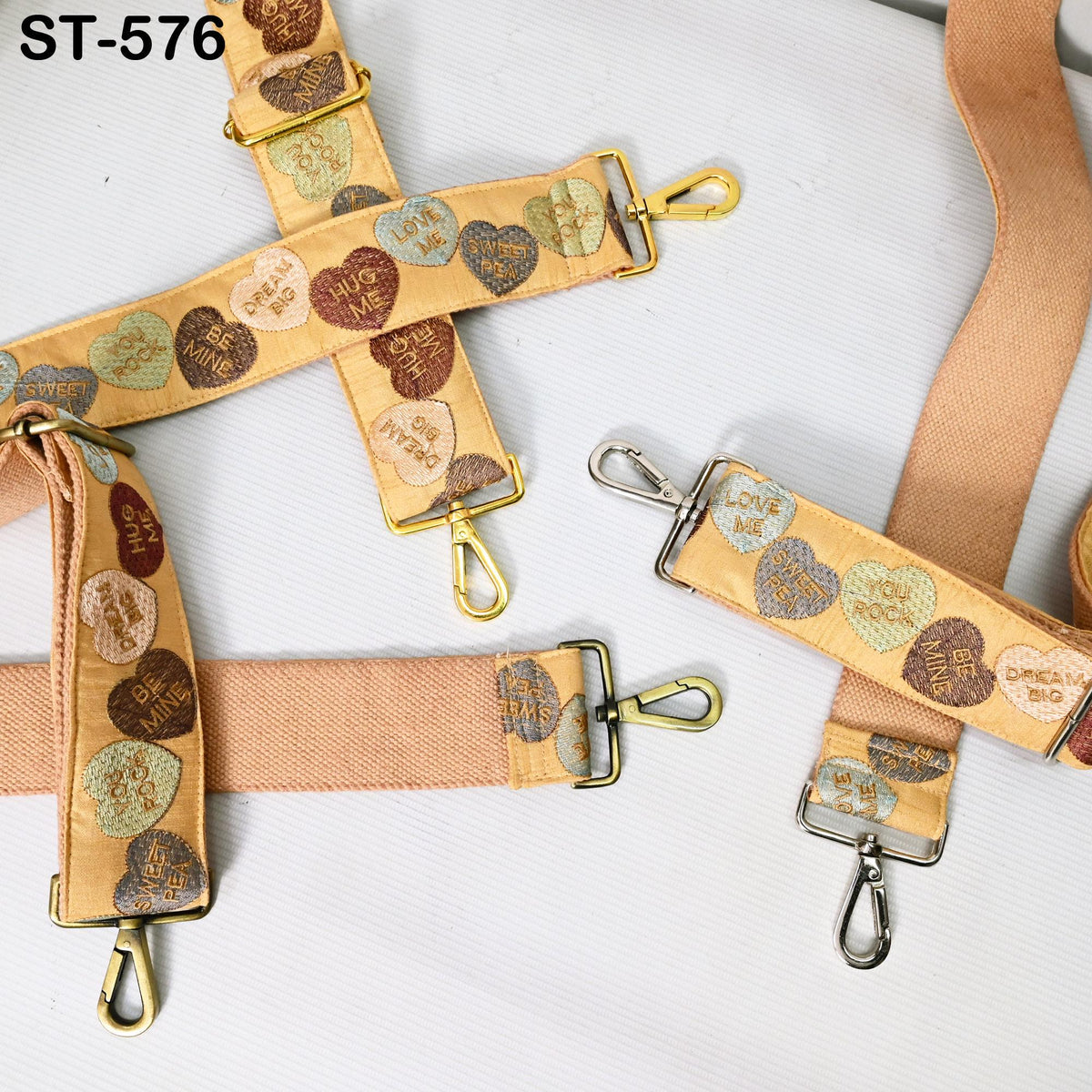 a collection of heart-shaped straps or straps with various designs and patterns, including some with the words "LOVE" and "BE" printed on them.