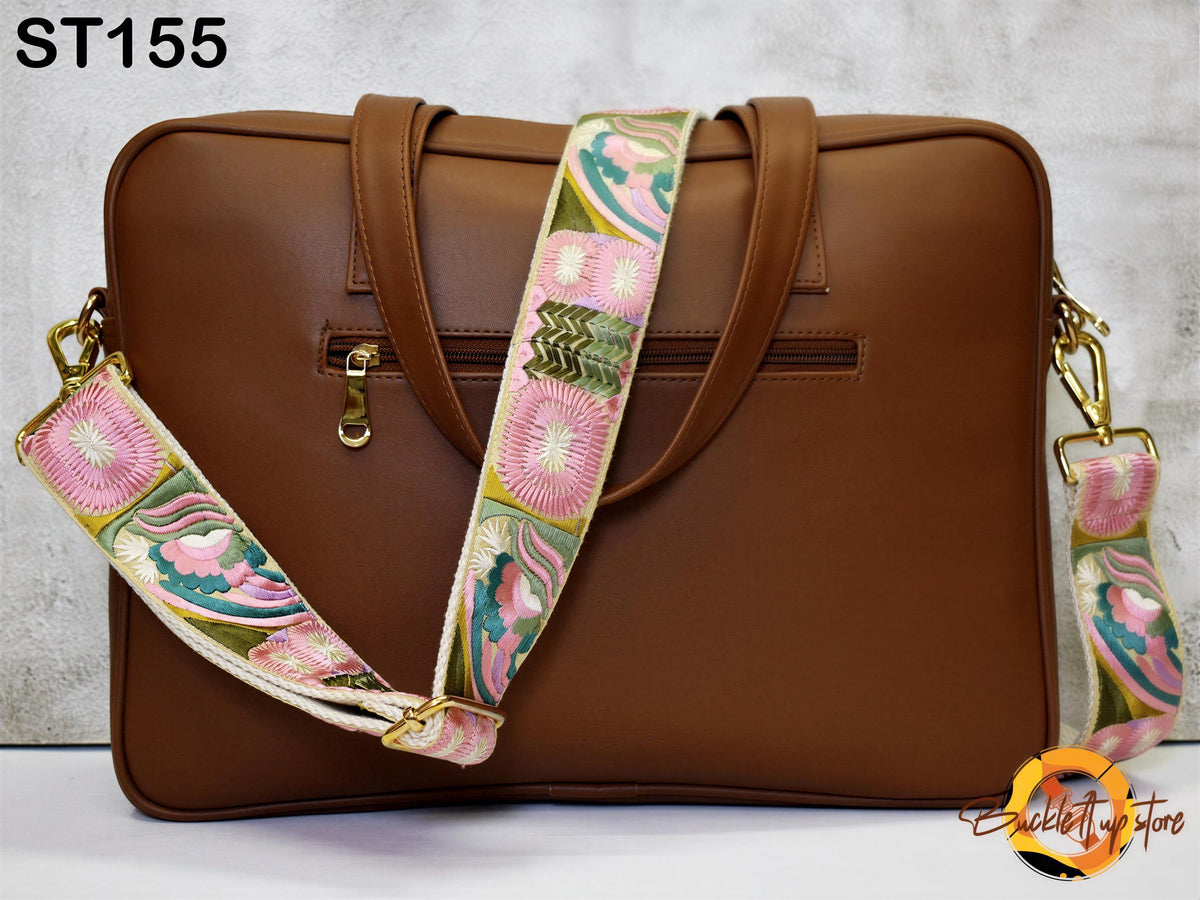 A brown leather laptop bag with a floral patterned strap and a zipper closure.