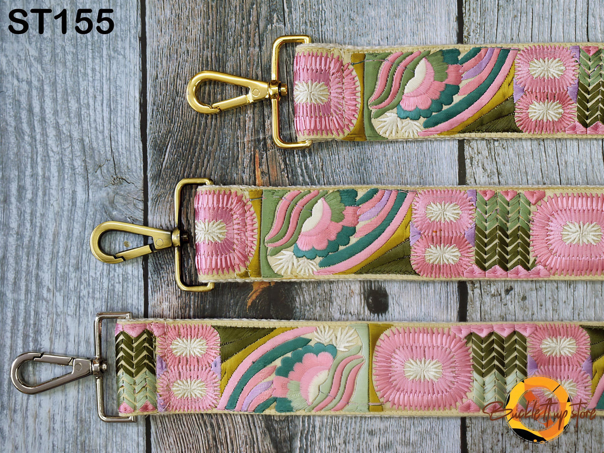 three colorful straps with floral patterns, each with a gold metal clasp and hook. The straps are arranged on a wooden surface.