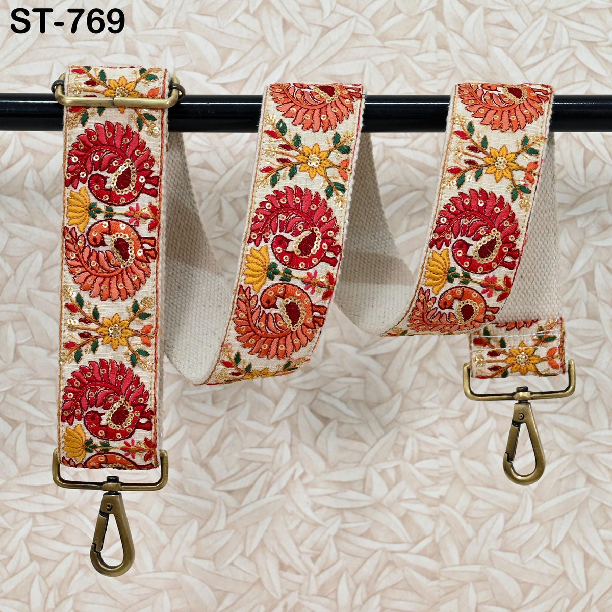 A colorful, floral-patterned strap with a metal clasp and hook attached to a black metal bar.
