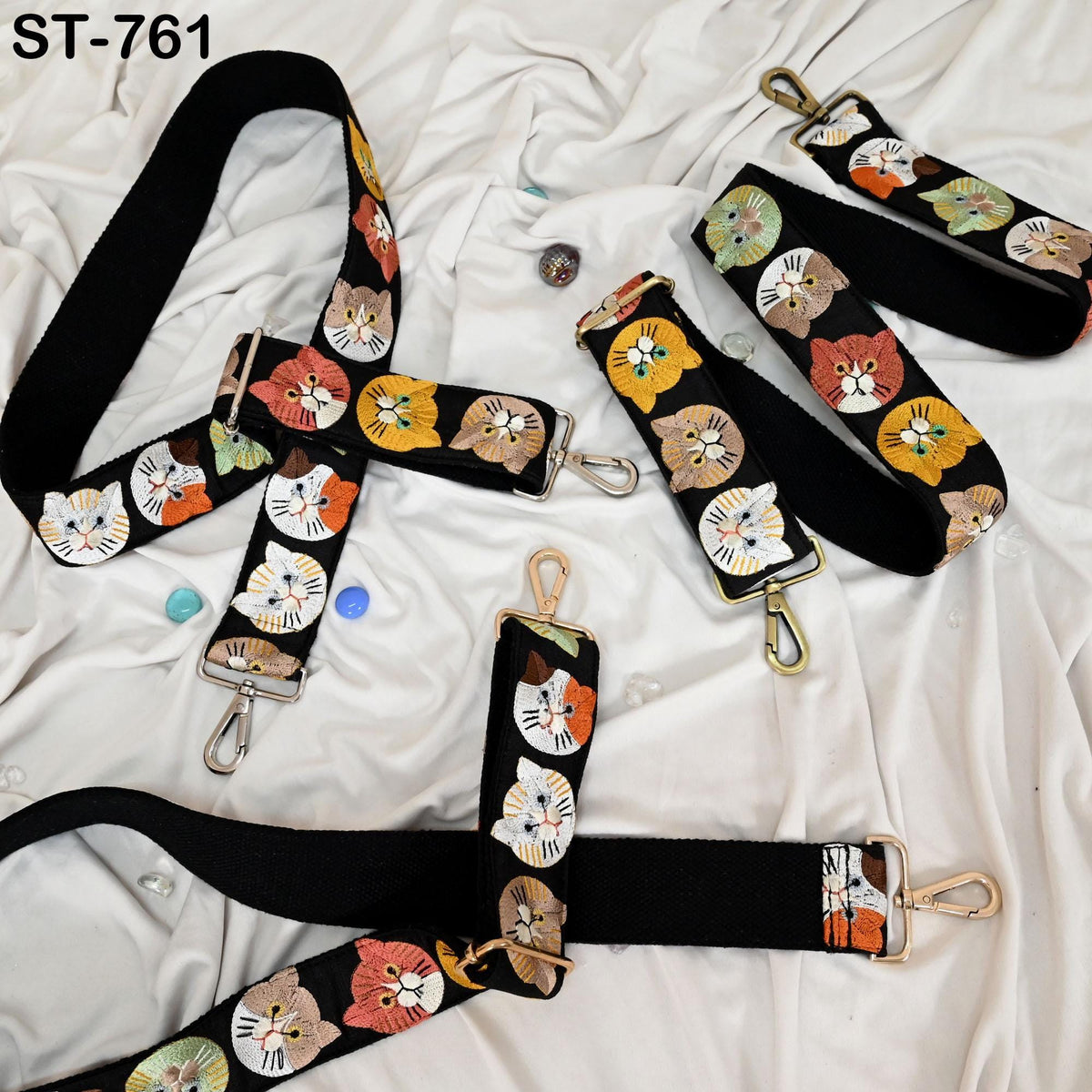 a collection of cat-themed straps and buckles, including a black strap with a cat face design and several other straps with cat faces.