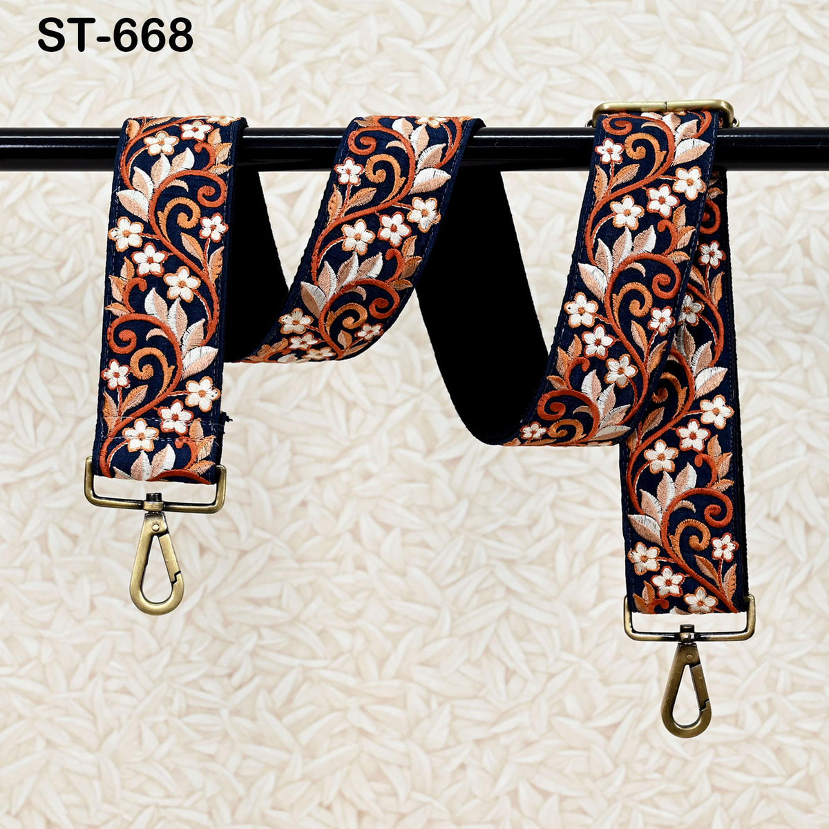 A pair of decorative straps with floral patterns in shades of blue, orange, and white, hanging on a black rod.