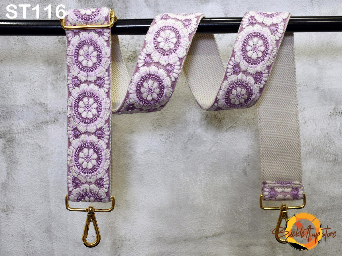 a strap with a floral pattern in shades of purple and white, hanging on a black bar.