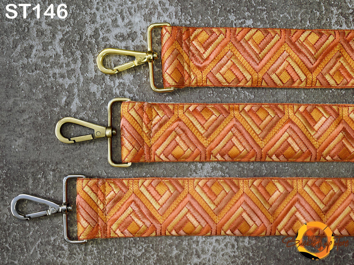 three straps with a geometric pattern in shades of orange and yellow, arranged on a gray surface.