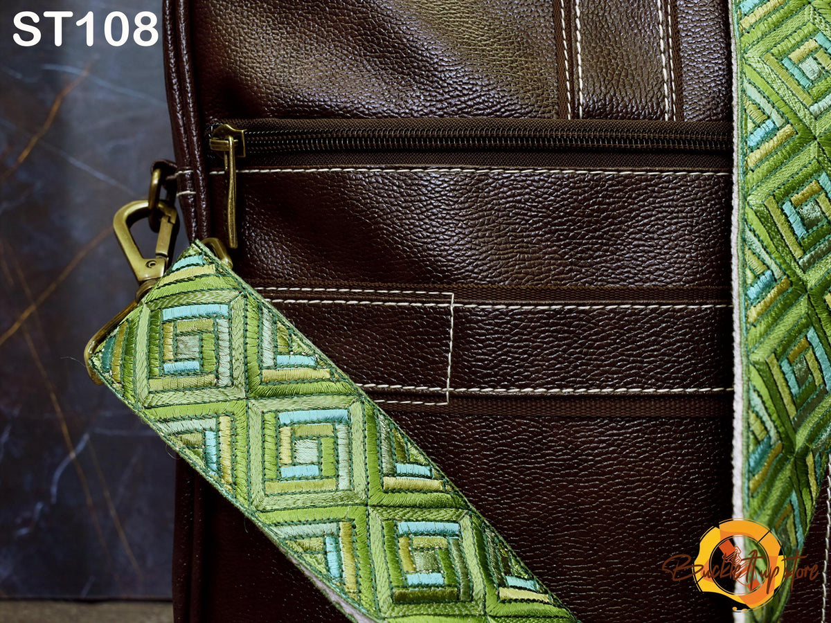 a close-up view of a brown leather bag with a green and blue patterned strap.