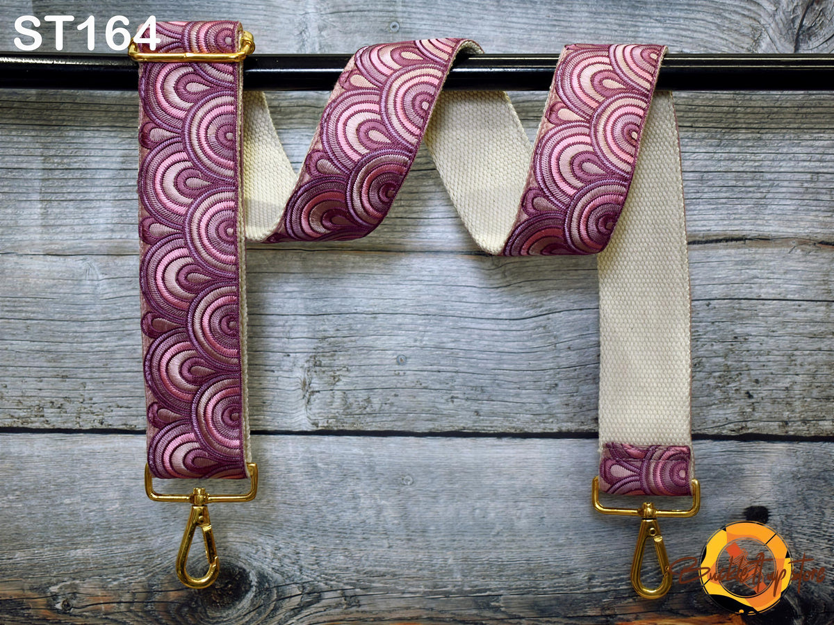 A colorful strap with a pattern of pink and purple circles is hanging on a wooden surface.