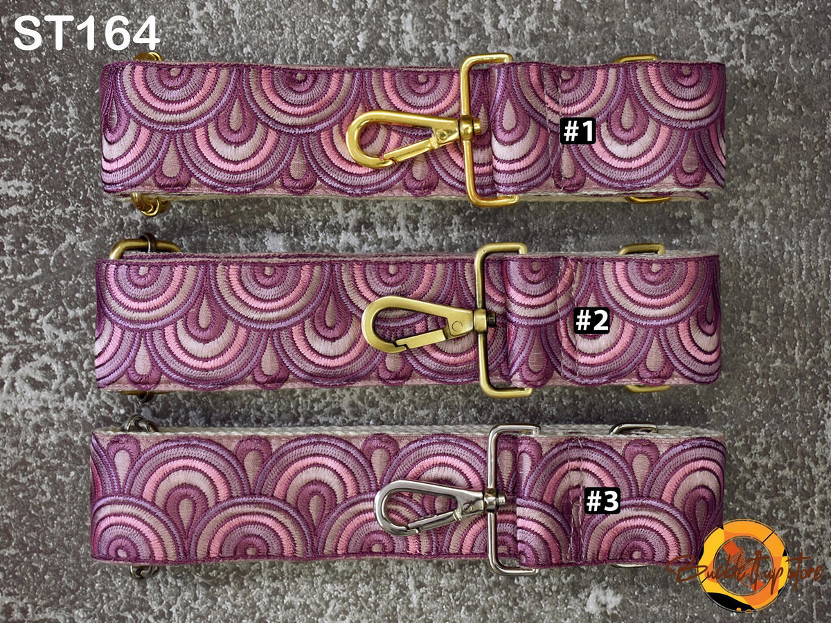 three colorful straps with a repeating pattern of pink and purple circles, each with a gold buckle and tag.