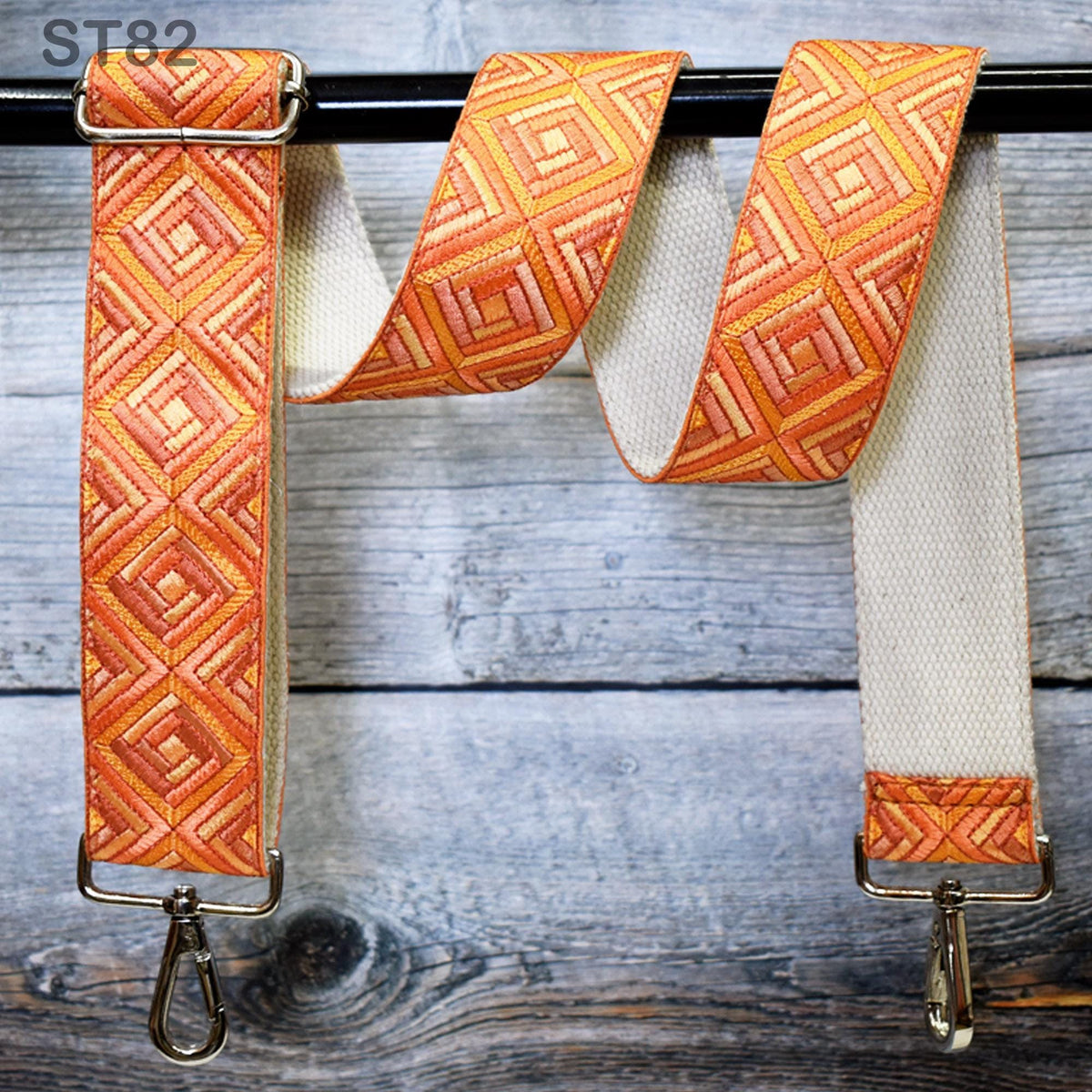 A colorful, patterned strap with a metal hook attached, hanging on a wooden surface.
