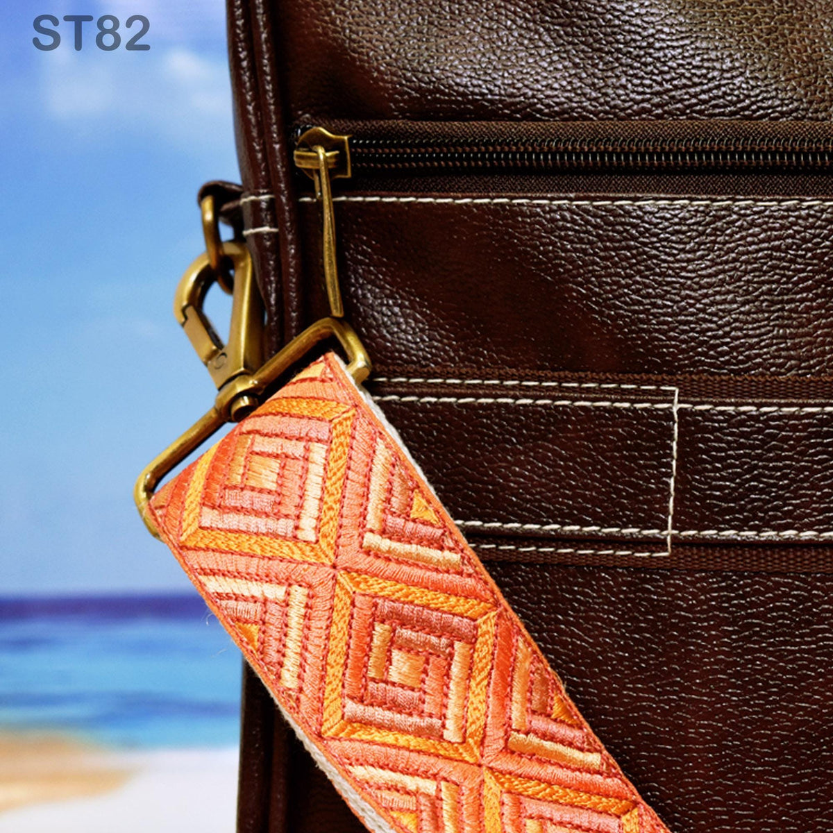 A close-up view of a brown leather bag with a zipper closure and a colorful strap.