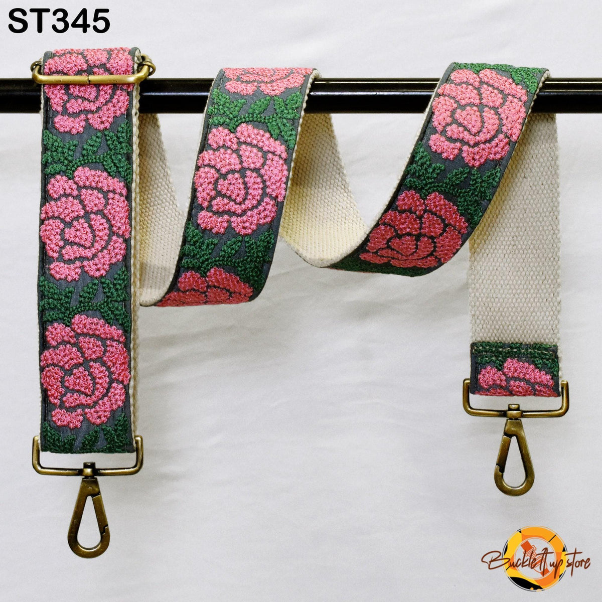 A floral-patterned strap with pink flowers and green leaves, hanging on a black bar.