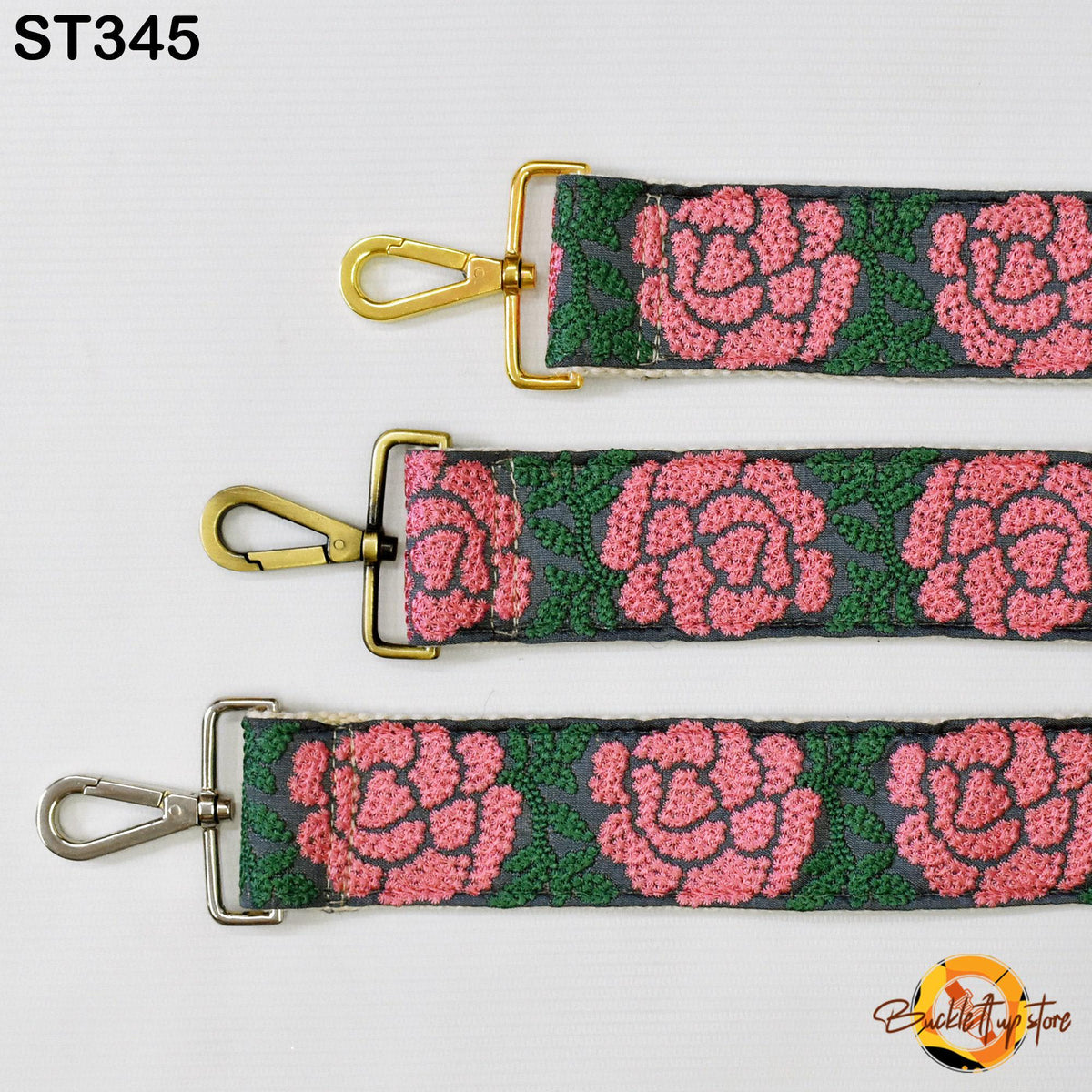 three straps with floral patterns in shades of pink and green. The straps have gold metal buckles and hooks, and the straps are arranged in a row.