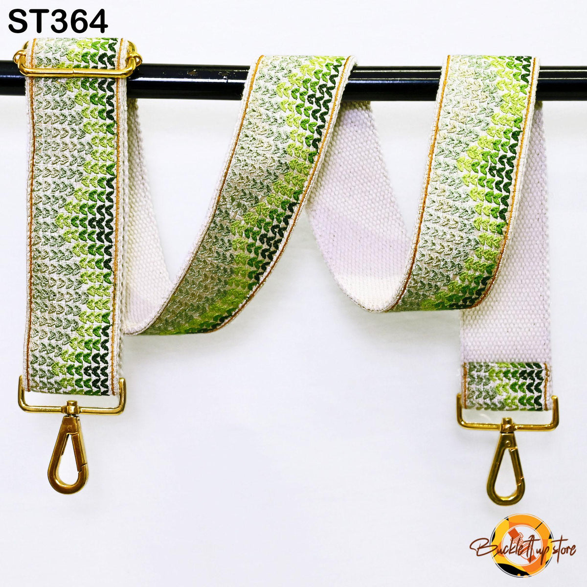 a strap with a green and white patterned design, hanging on a black rod.