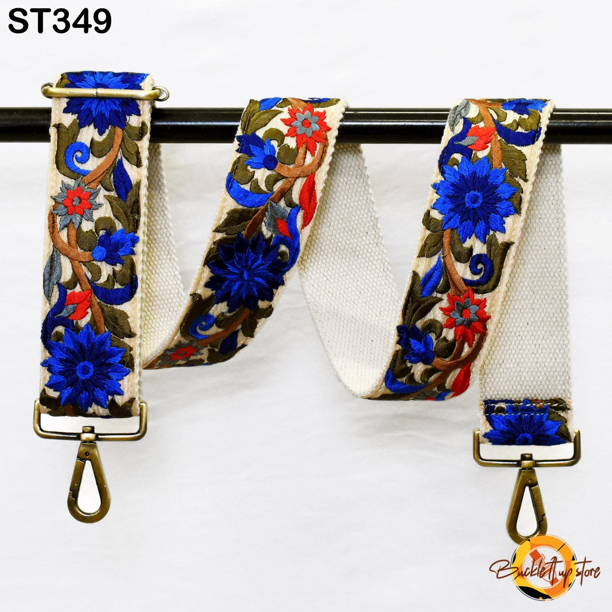A decorative floral embroidered strap with blue and red flowers, attached to a black metal hook.