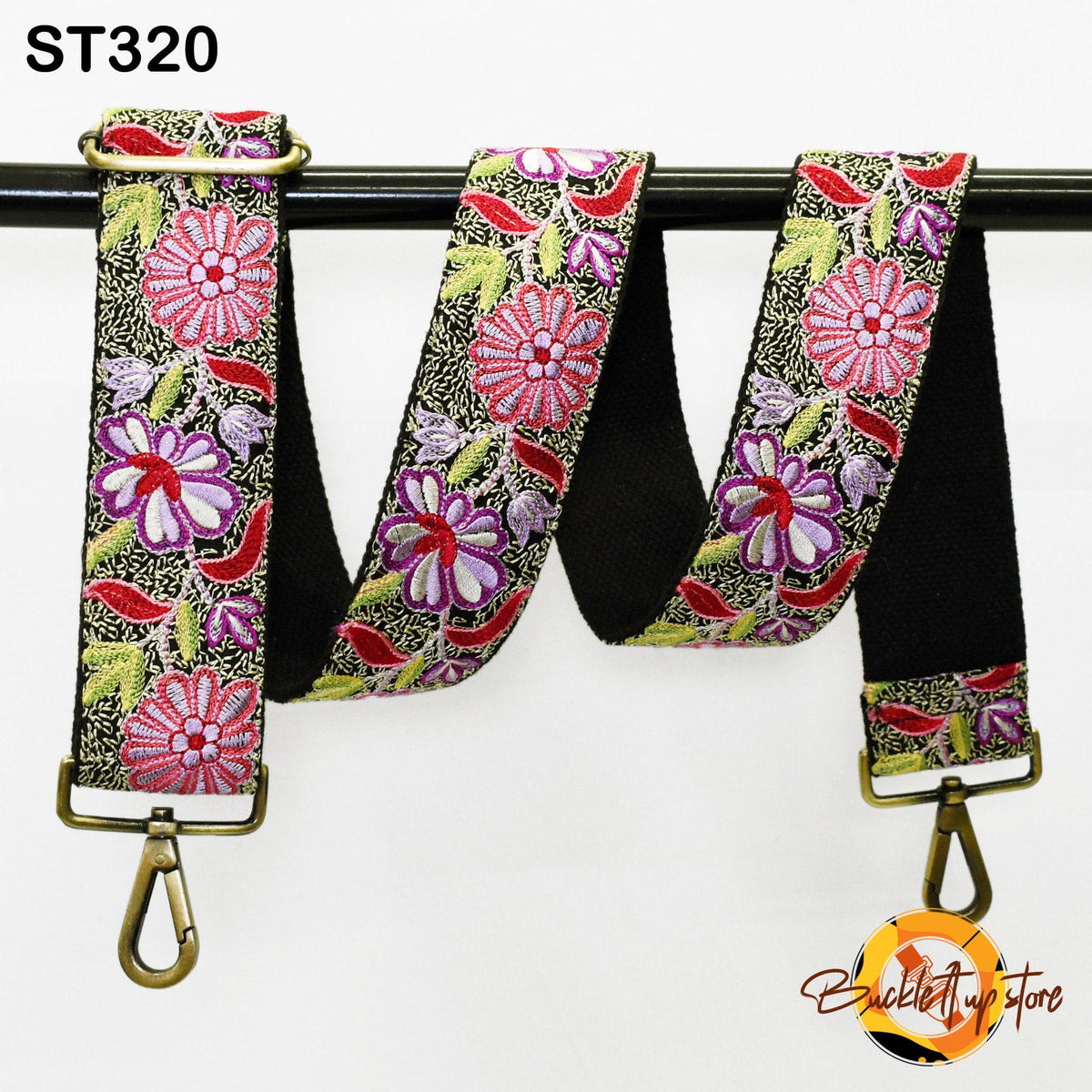 A colorful floral patterned strap with a black metal buckle, hanging on a black metal hook.
