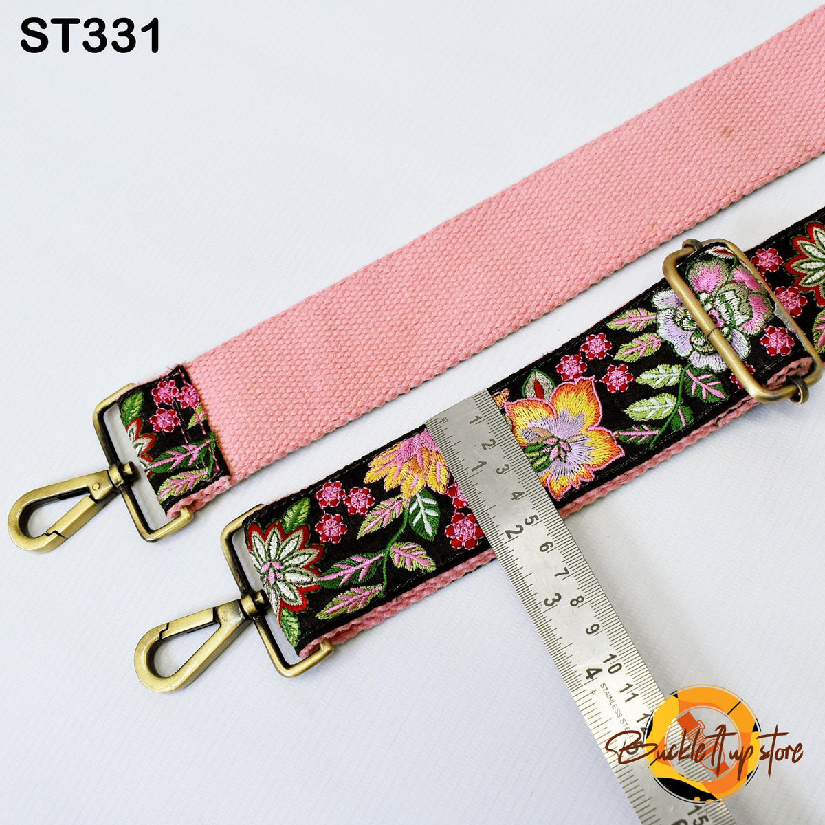 a pink strap with a floral pattern and a metal ruler placed on top of it.