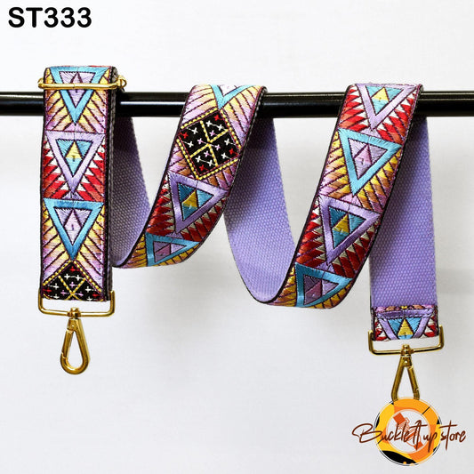 A colorful, patterned strap with geometric designs in various shades of purple, red, and yellow, hanging from a black metal hook.