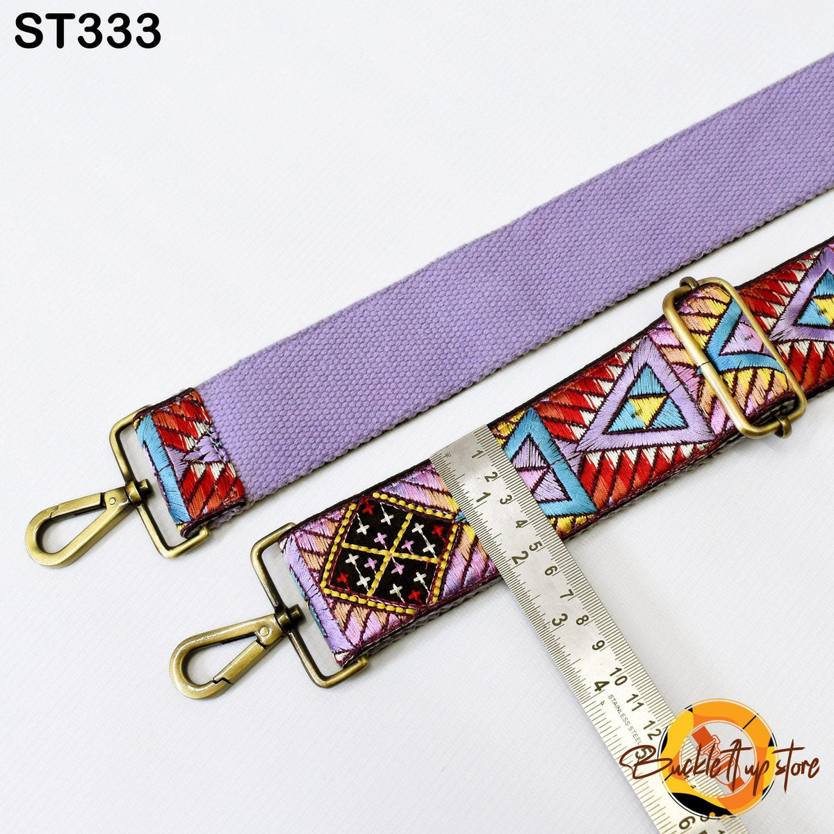 a purple strap with a colorful, geometric pattern, and a ruler is placed next to it, indicating the strap's length.