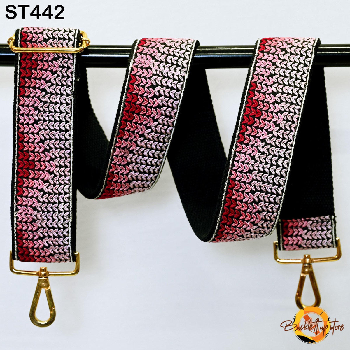 A colorful, knitted-patterned strap with a black and red striped pattern, hanging from a black metal hook.