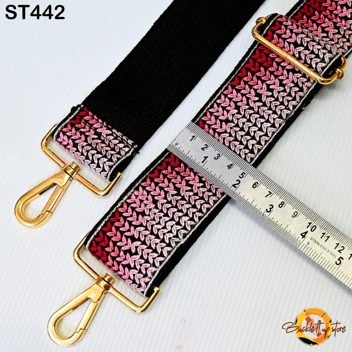a black and pink braided strap with a ruler placed on top of it, indicating the strap's length.