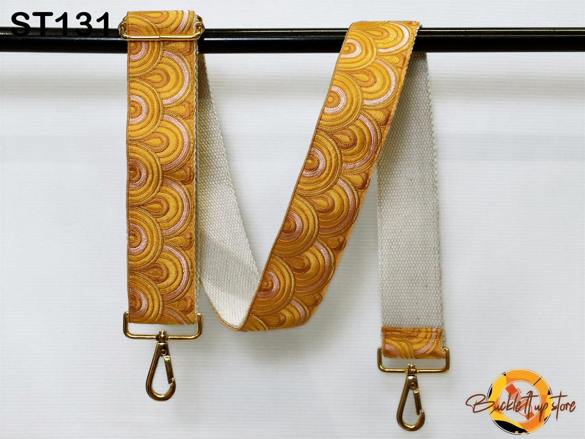 a colorful, patterned strap with a gold metal buckle attached to a black metal bar.